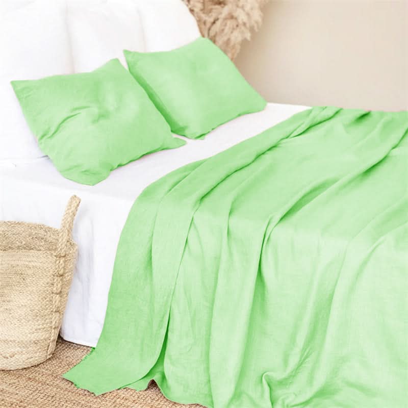 Lime green linen bed sheets with white base and pillows on a bed.