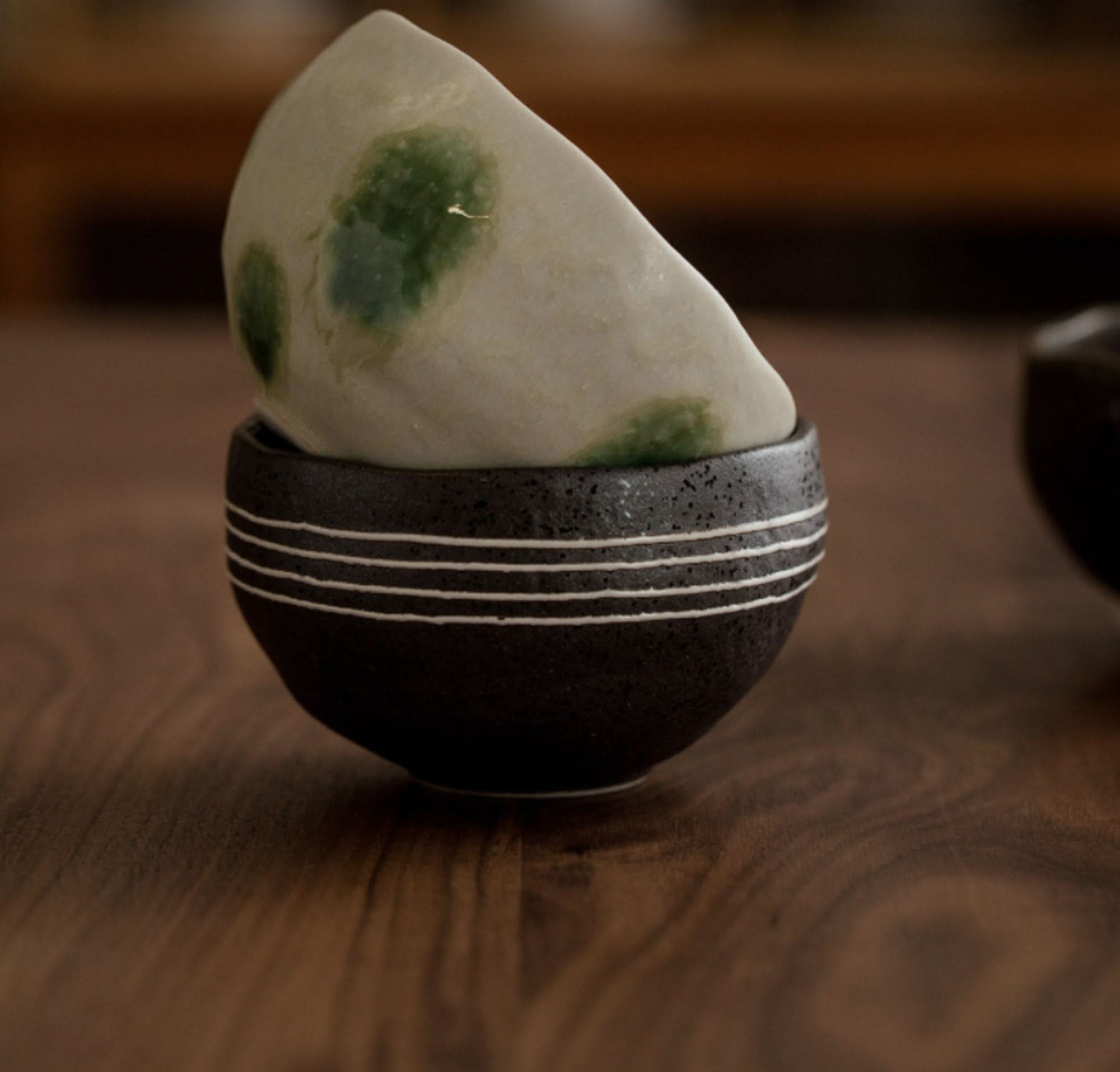 Japanese tea set: ceramic cup with white stripes and speckled dark exterior, light speckled interior with green accents.