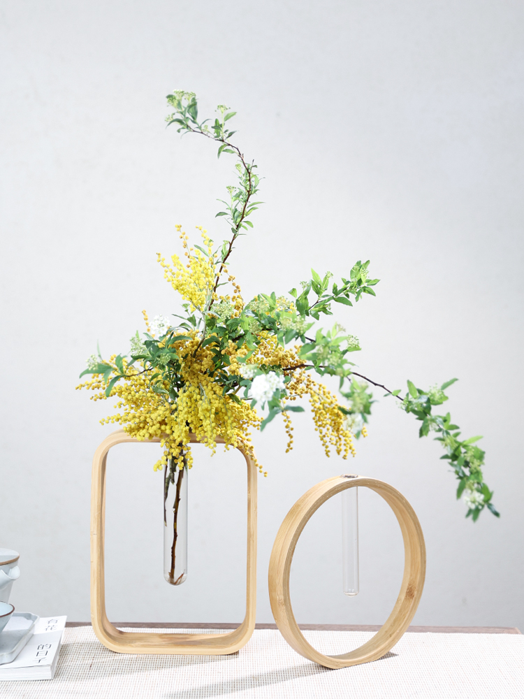 Minimalist wooden frame wall flower vase holding yellow and green floral arrangement.