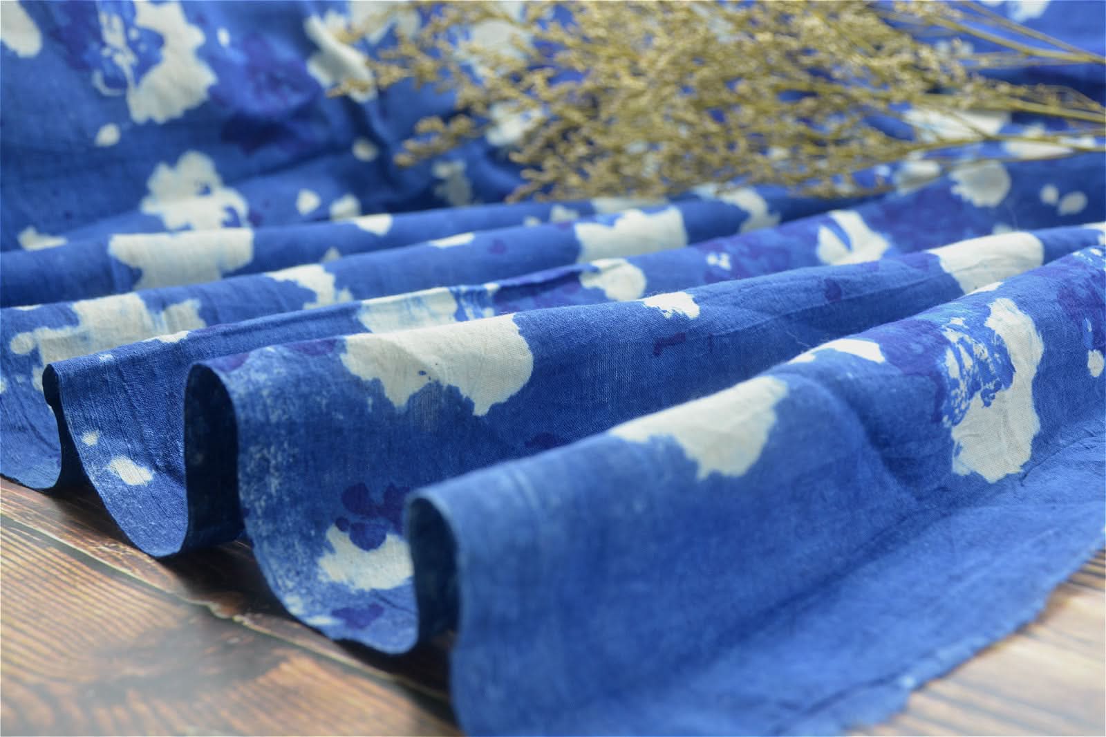 Indigo plant dyed Indian fabric with white abstract pattern, draped on wood.