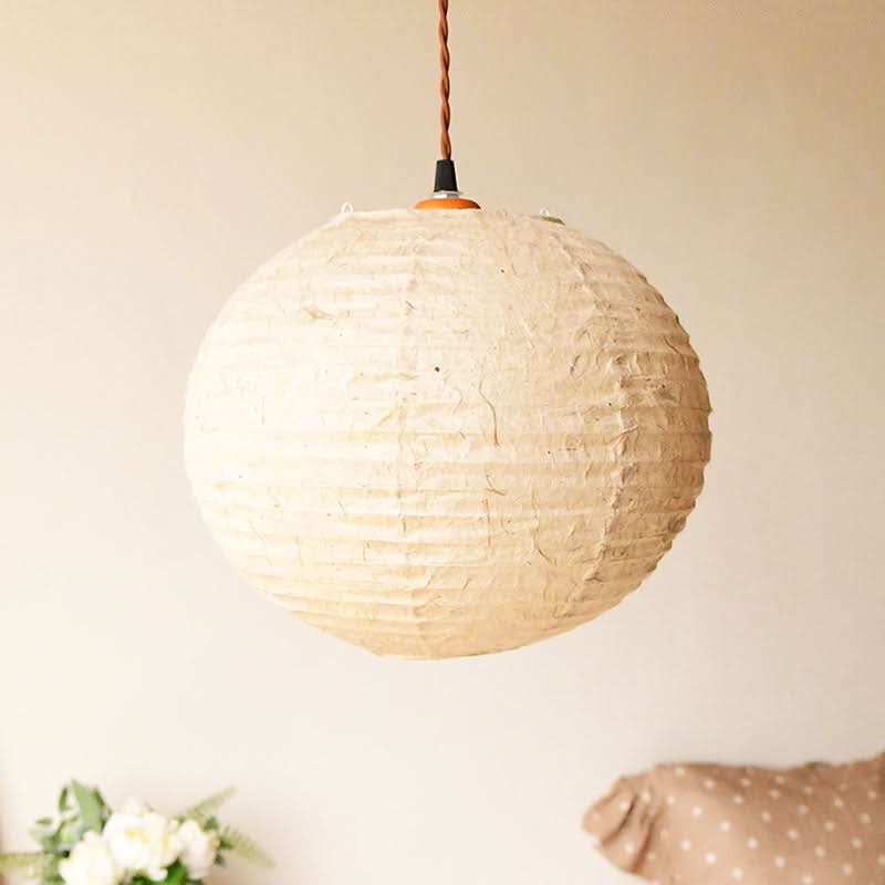 Cream textured handmade paper lampshade hanging in a cozy home decor setting.
