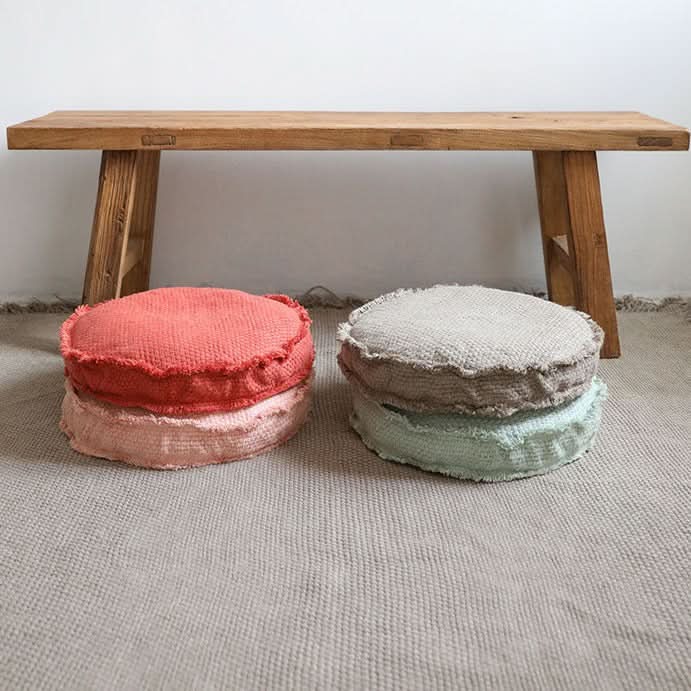 Coral & blush customizable textured floor cushion set by rustic wooden bench.