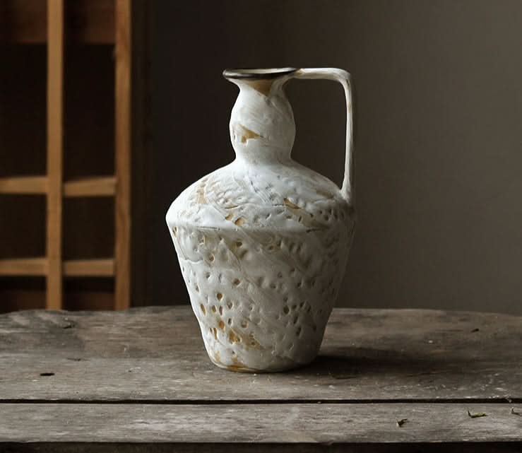 Wabi-sabi small ceramic vase with textured white finish on distressed wooden surface.