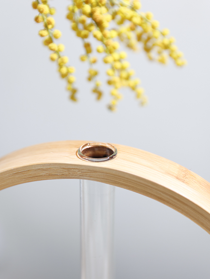 Modern Wall Flower Vase with bamboo frame and glass tube holding yellow flowers.