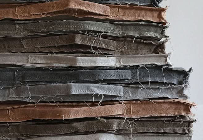 Customizable distressed squared linen cushions in muted earth tones, stacked.