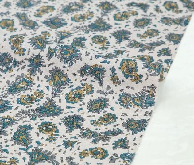 Muslin floral fabric in blue, gold, and gray on white for handmade crafts.