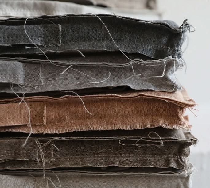Stack of customizable distressed linen cushions in gray and brown tones.