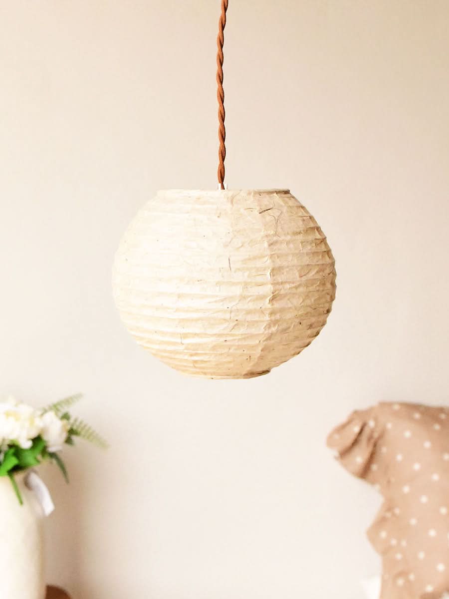 Cream handmade paper lampshade hanging with brown cord, home decor accent.