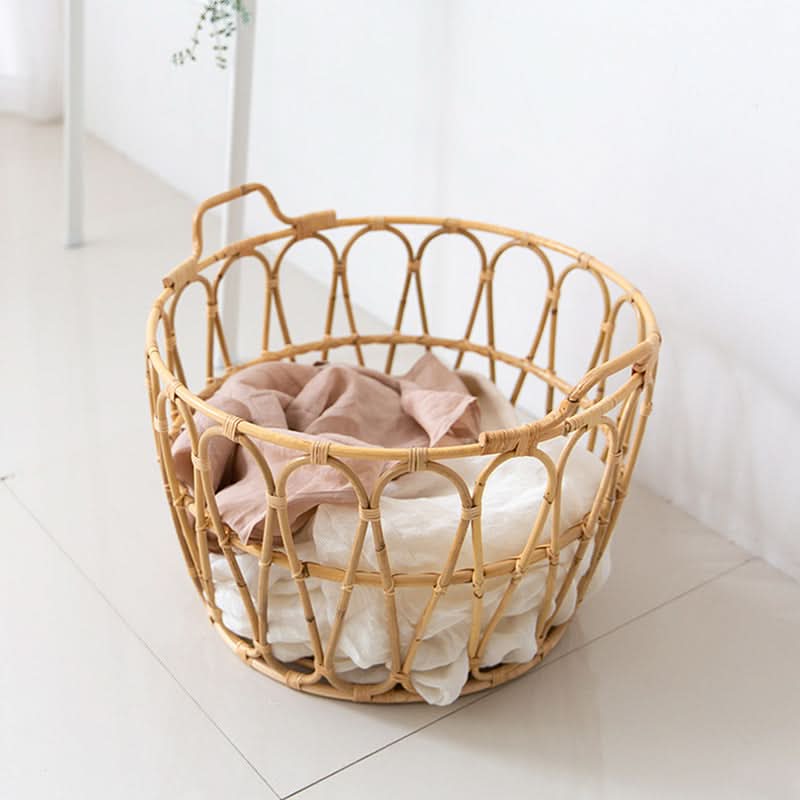 Natural rattan round storage basket with zig-zag pattern, holding soft linens.