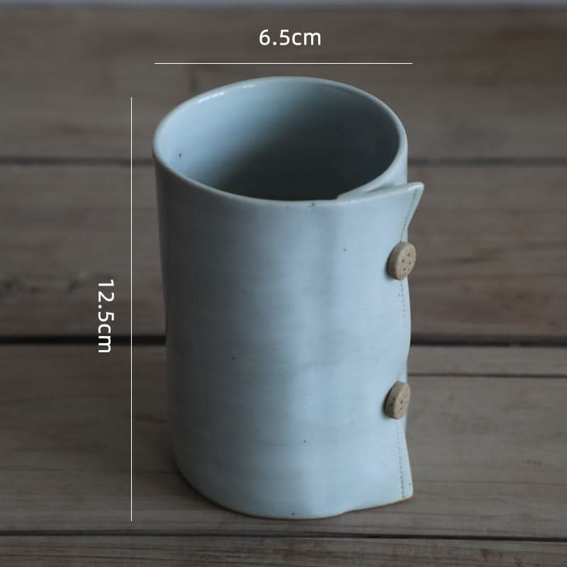 Grey ceramic cup with textile folded style, featuring button details. Coffee mug.