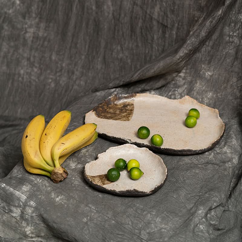 Wabi-sabi Irregular Beige Serving Tray with limes and bananas on a textured gray cloth.