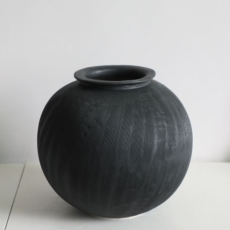 Black ceramic vase with subtle vertical texture, a minimalist home decor accent.