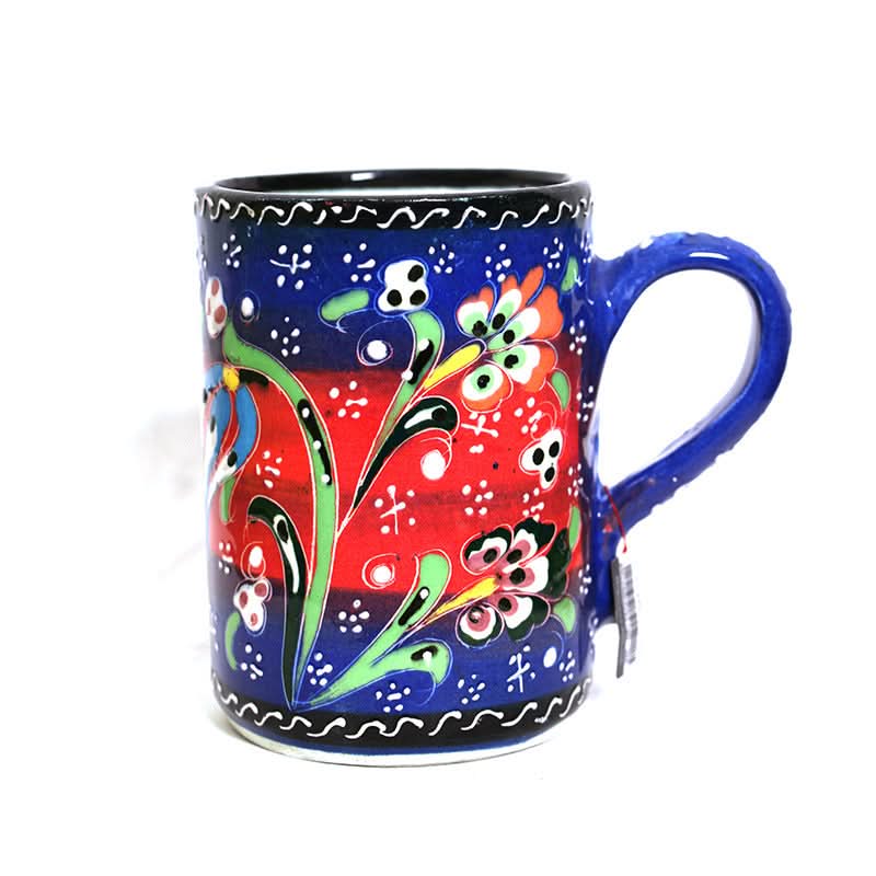 Vibrant Turkish glazed ceramic mug with floral designs in red, blue, and green on a white background.