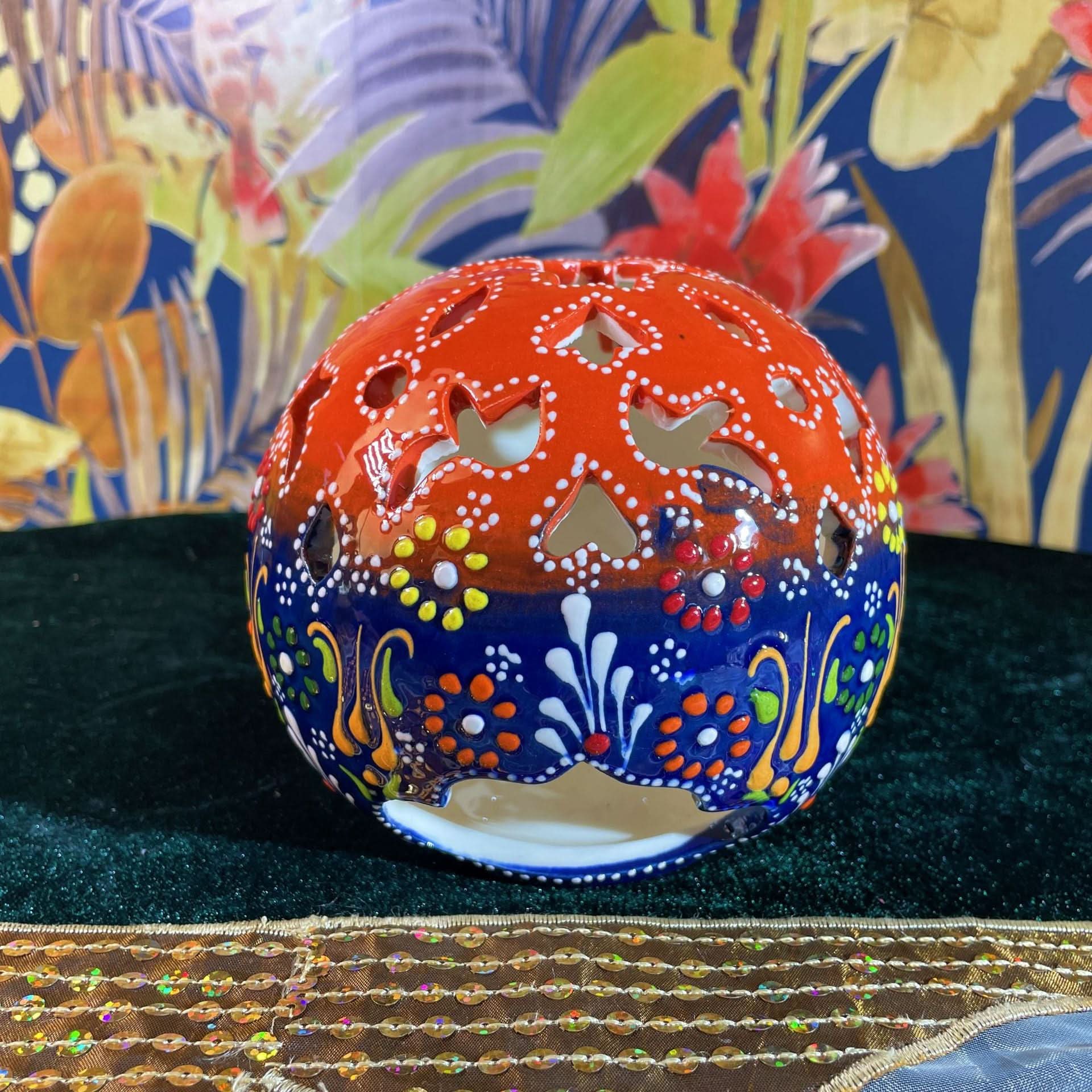 Vibrant Turkish ceramic hand-painted candle holder with floral motifs, on dark green fabric.