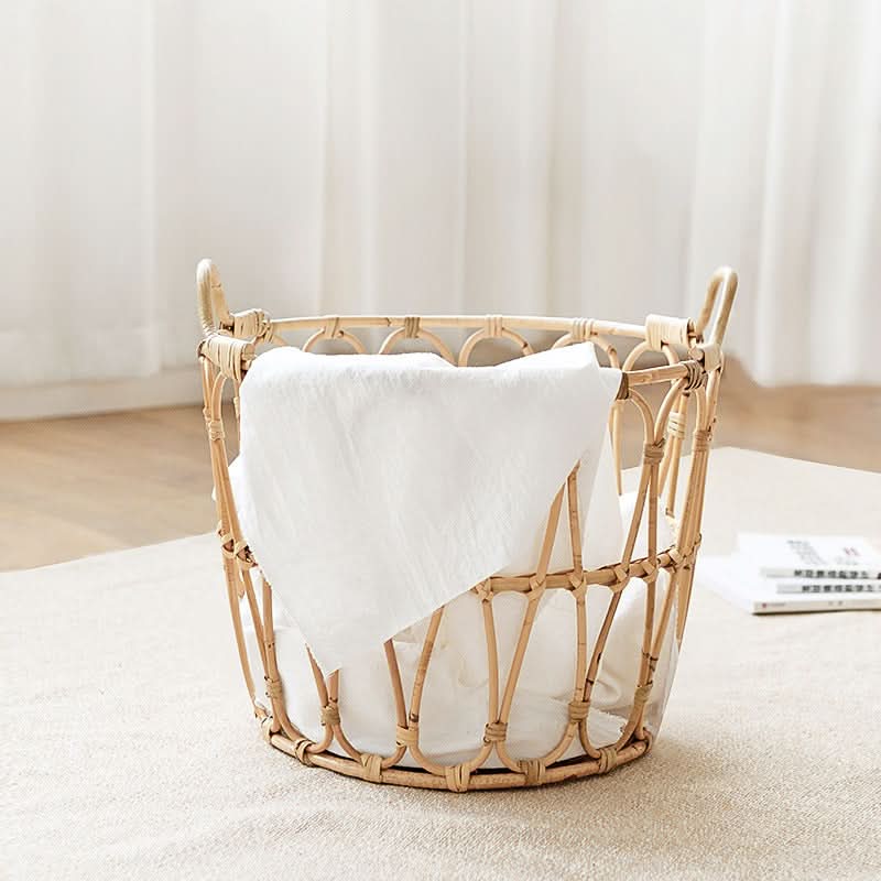 Natural rattan round storage basket with zig zag pattern and white linen inside on a light rug.