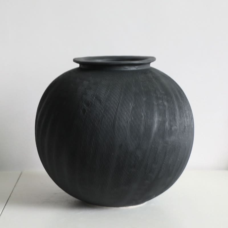 Textured black ceramic vase, a round home decor piece with a ribbed surface.