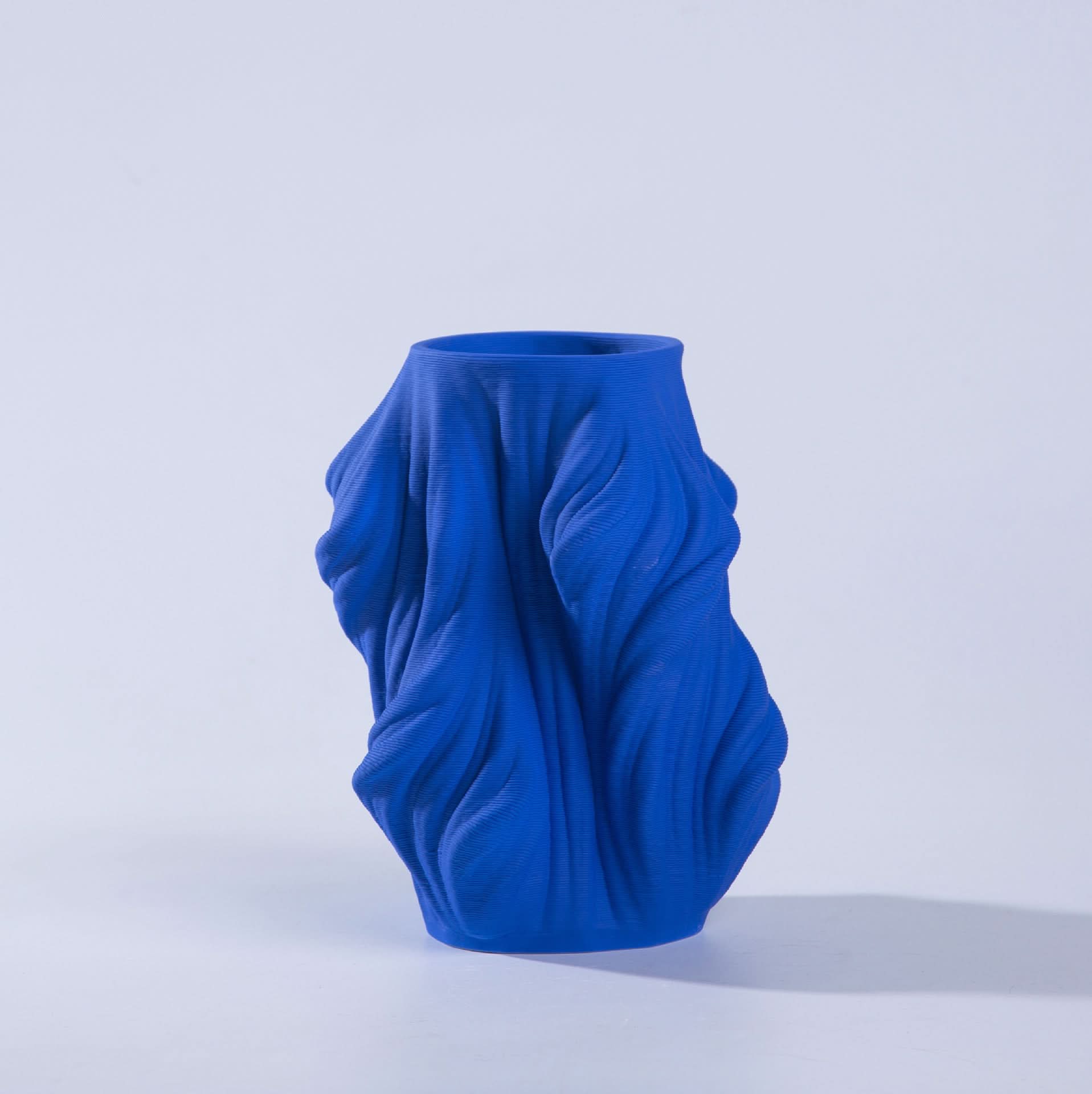 Vibrant blue 3D printed vase with draped fabric texture, ceramic material, home decor.