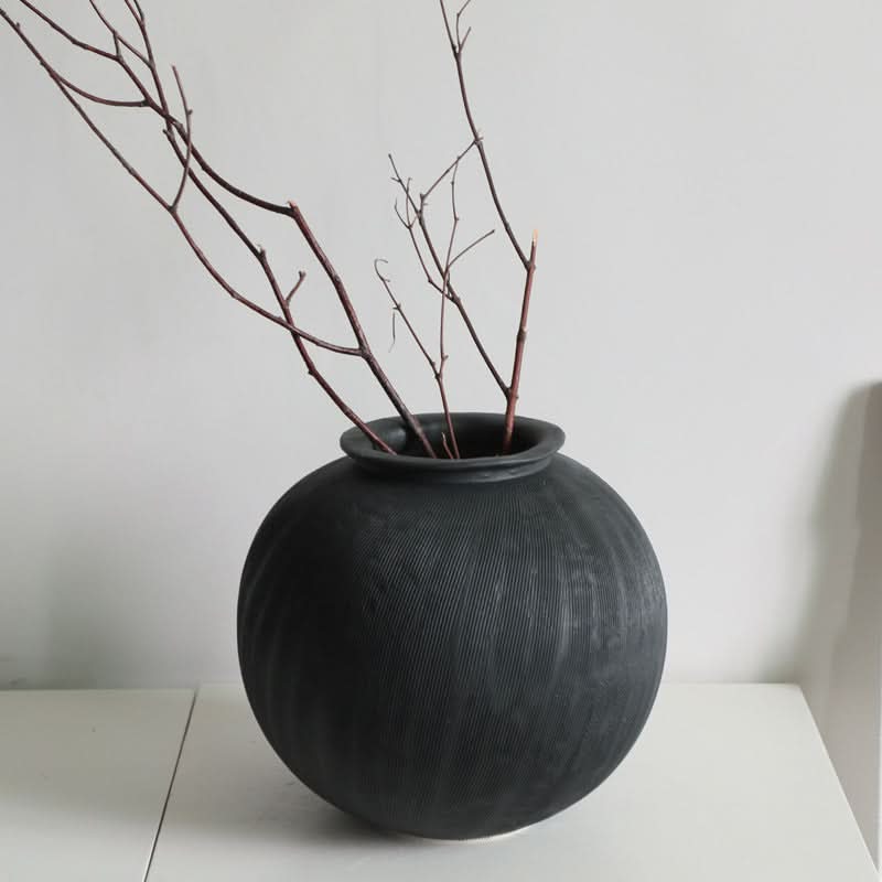 Textured black ceramic vase with branches, home decor essential.