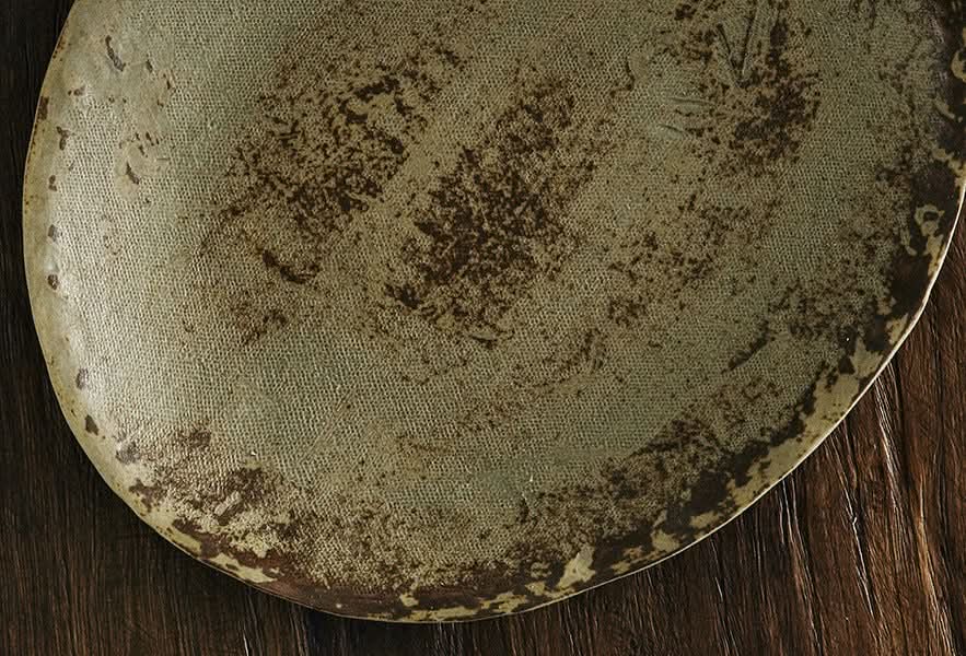 Unglazed ceramic plates with cloth texture, rustic brown and beige hues on wooden surface.