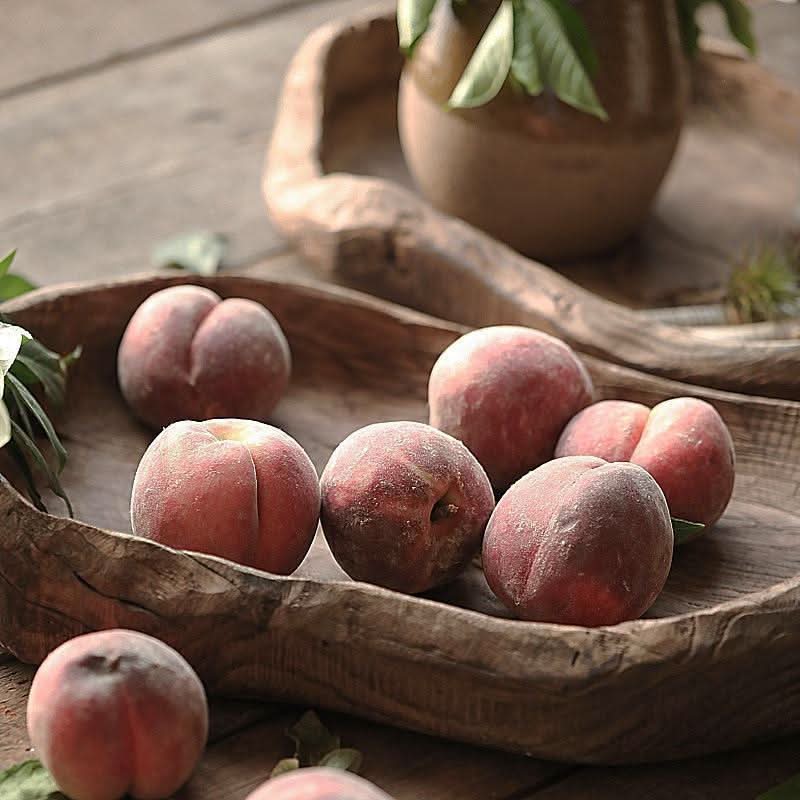 Wooden Distressed Serving Bowl holding ripe peaches on a rustic wooden surface