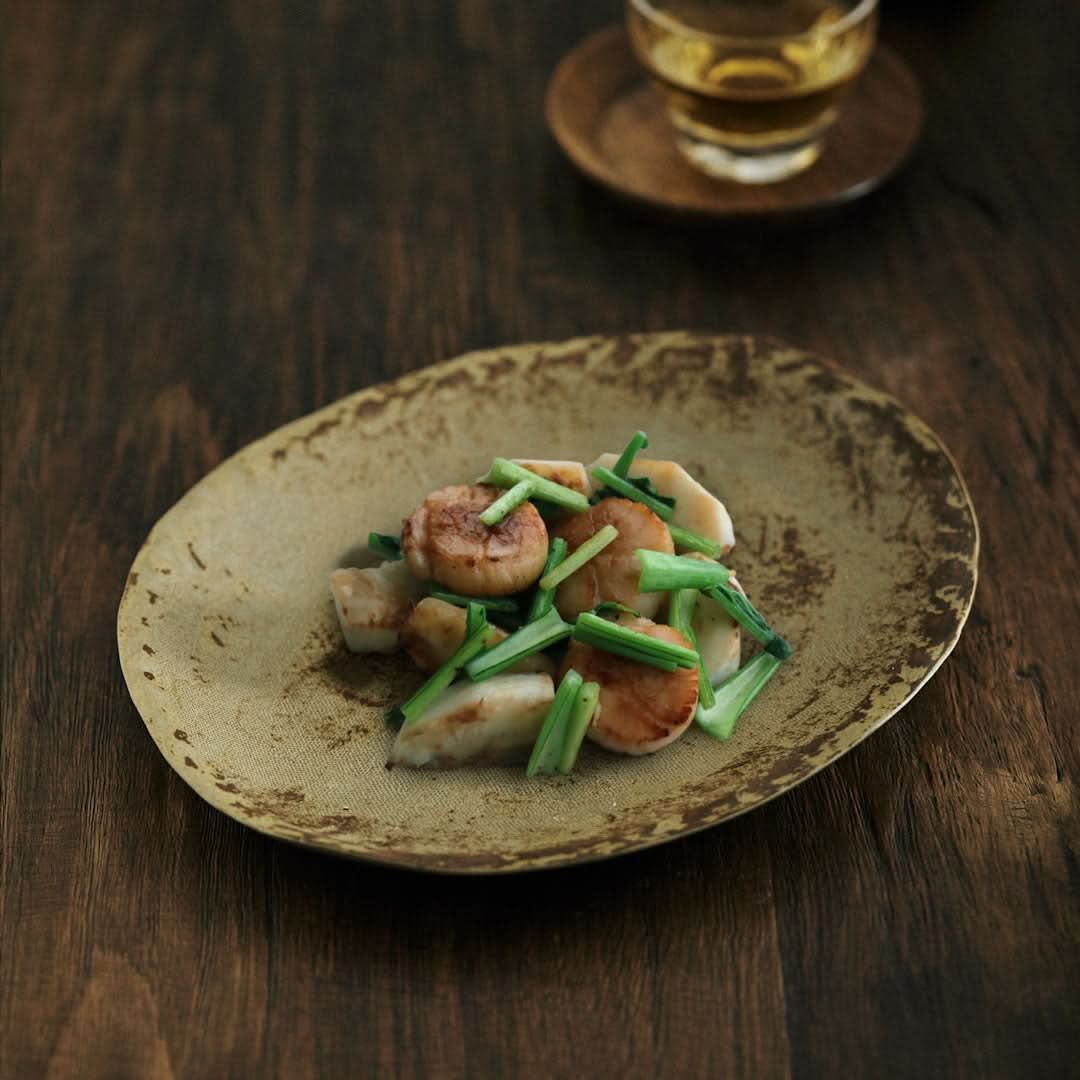 Unglazed ceramic plate with cloth texture, serving scallops and greens on wooden table