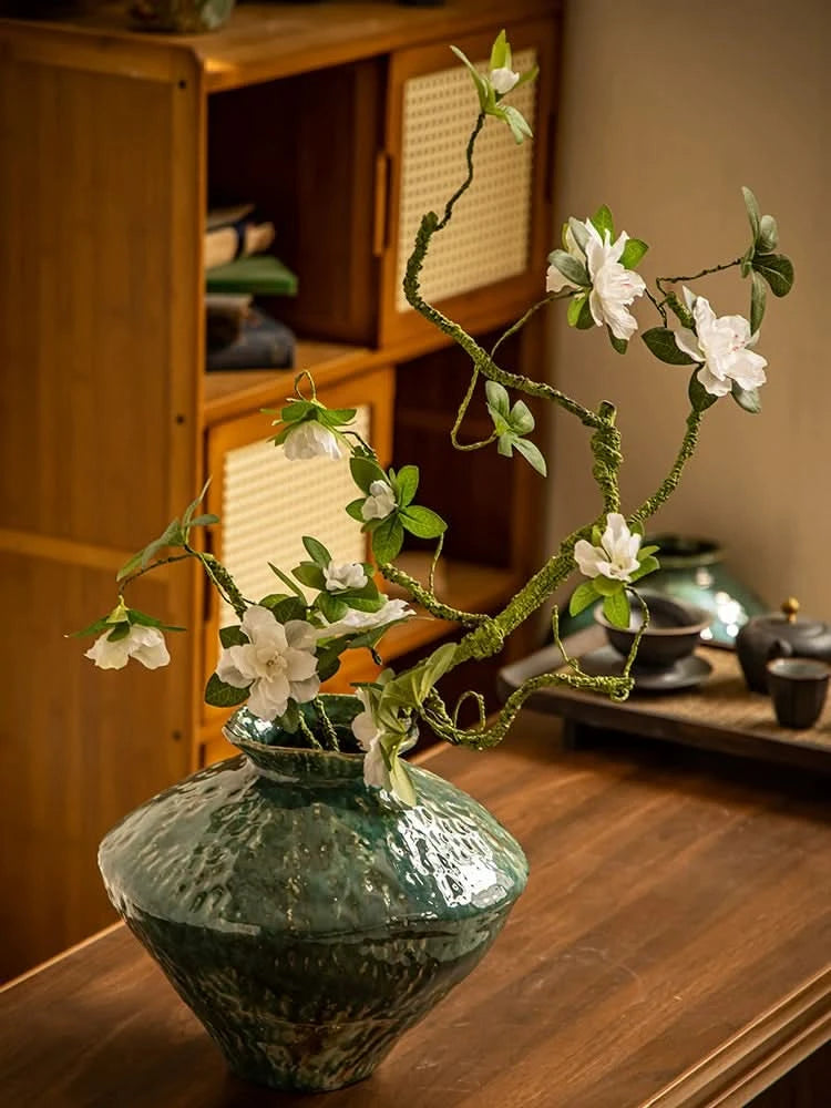 Wabi-Sabi Distressed Rustic Vase with Dark Green Glaze, featuring white flowers.