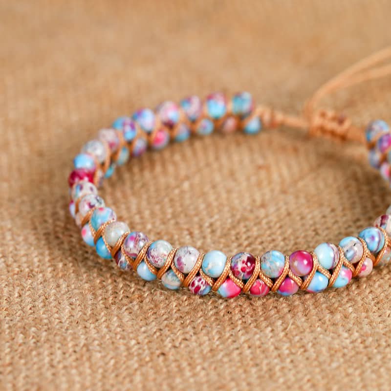 Emperor stone bracelet with 4mm multi-colored beads and braided cord on burlap.