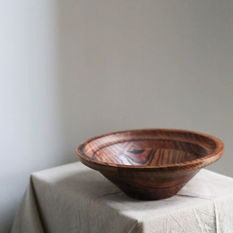 Handmade retro bowl made of rich, dark wood with visible grain, placed on a light linen cloth.