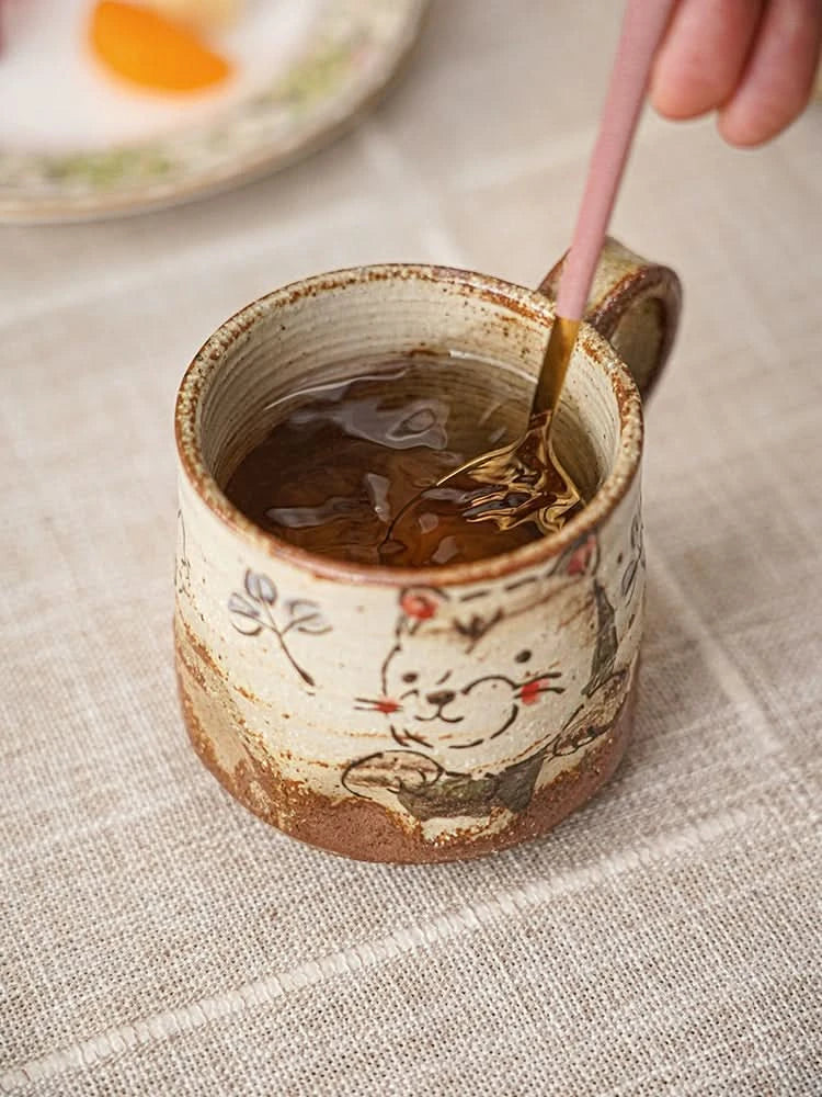 Hand painted coffee mug 11oz with a cute cat design, filled with tea, on a linen tablecloth.