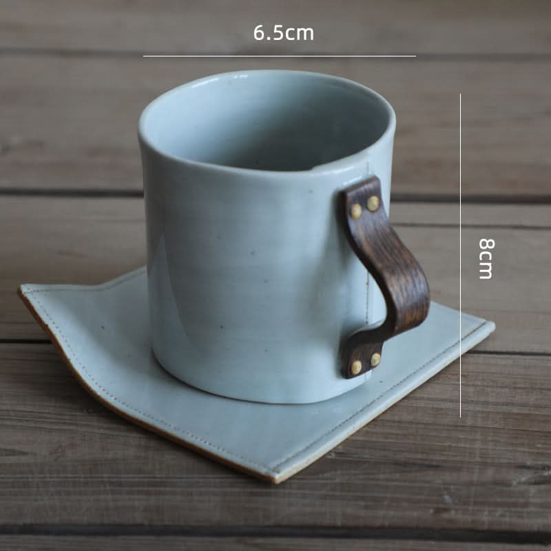 Grey ceramic coffee mug with textile folded style saucer and wooden handle.