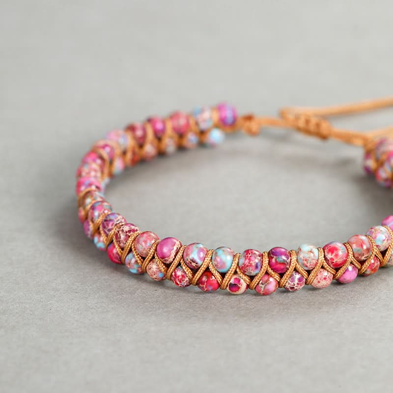 Emperor stone bracelet with 4mm pink, blue, and purple beads on a tan cord.