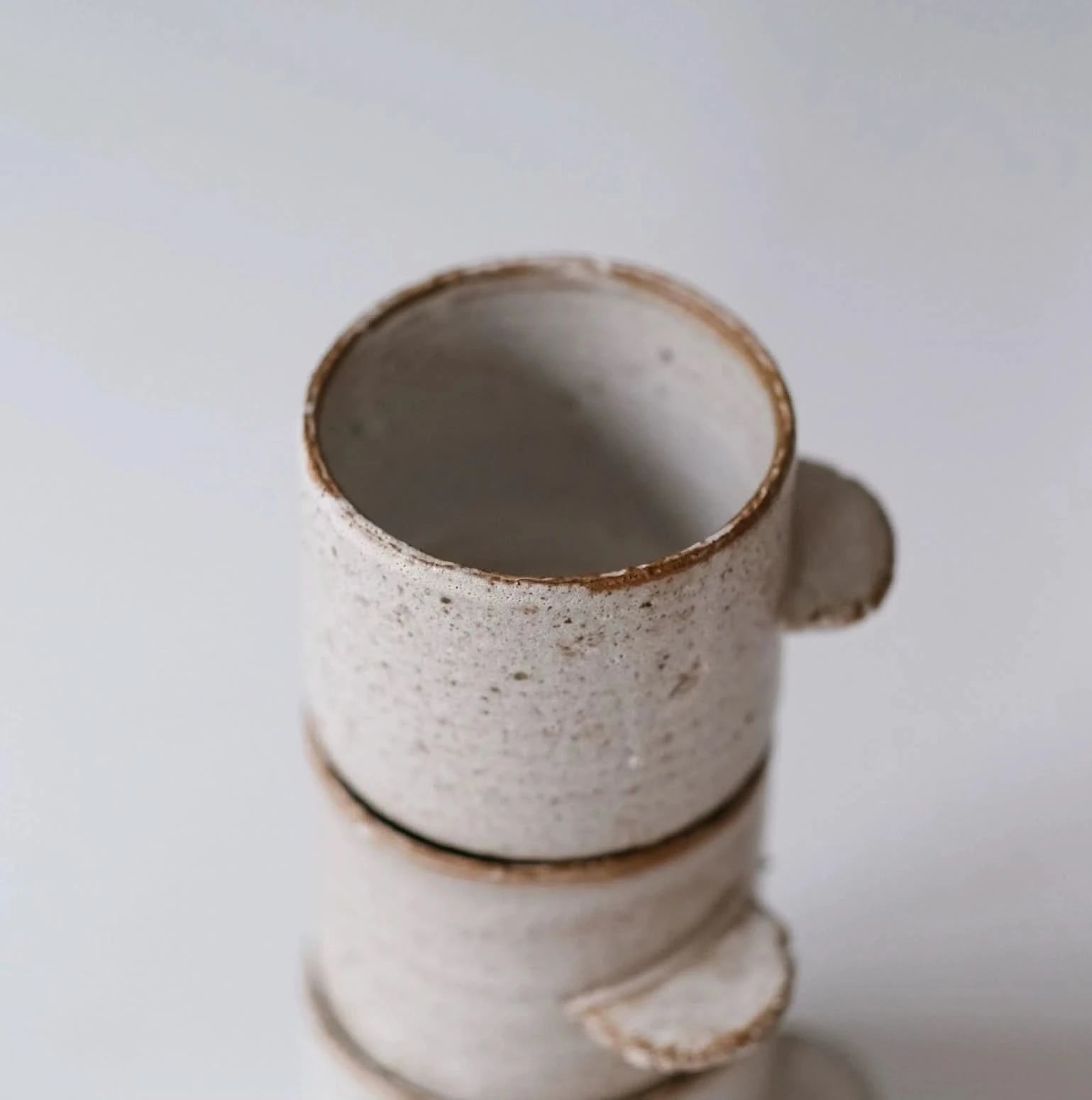 Rough pottery ceramic mug with straight handle, speckled white finish, home decor.