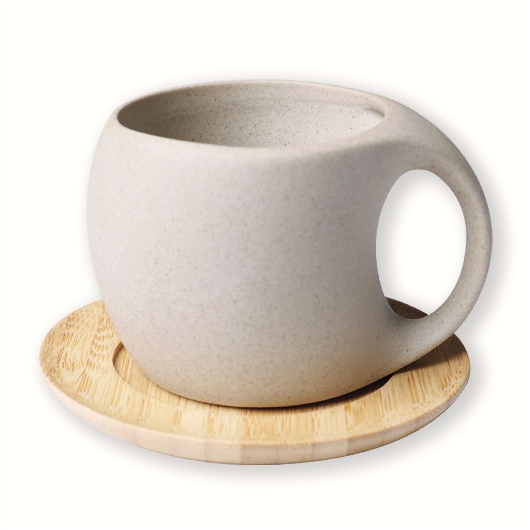 Abstract ceramic mug with arched handle on wooden saucer.