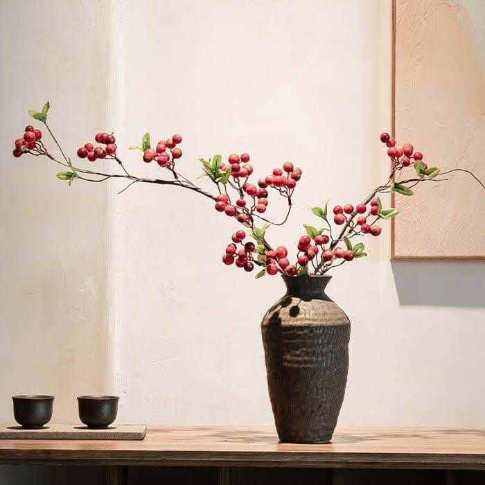 Abstract geometric ceramic vase with hammered texture, displaying red berries.