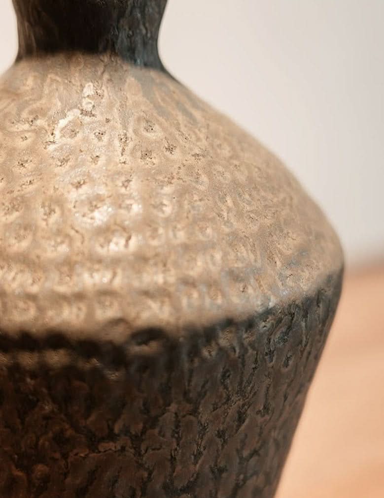 Abstract geometric ceramic vase with hammered texture in metallic tones.