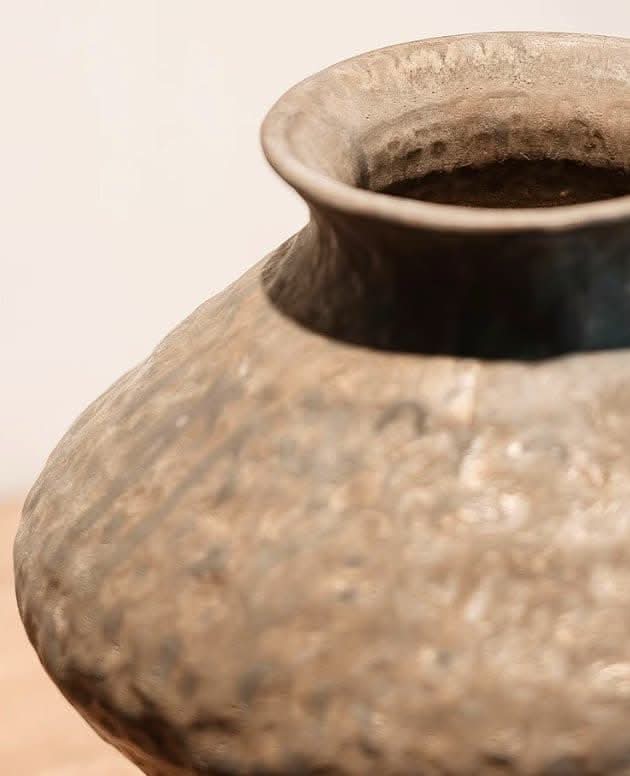 Abstract geometric ceramic vase with hammered texture in earthy tones.