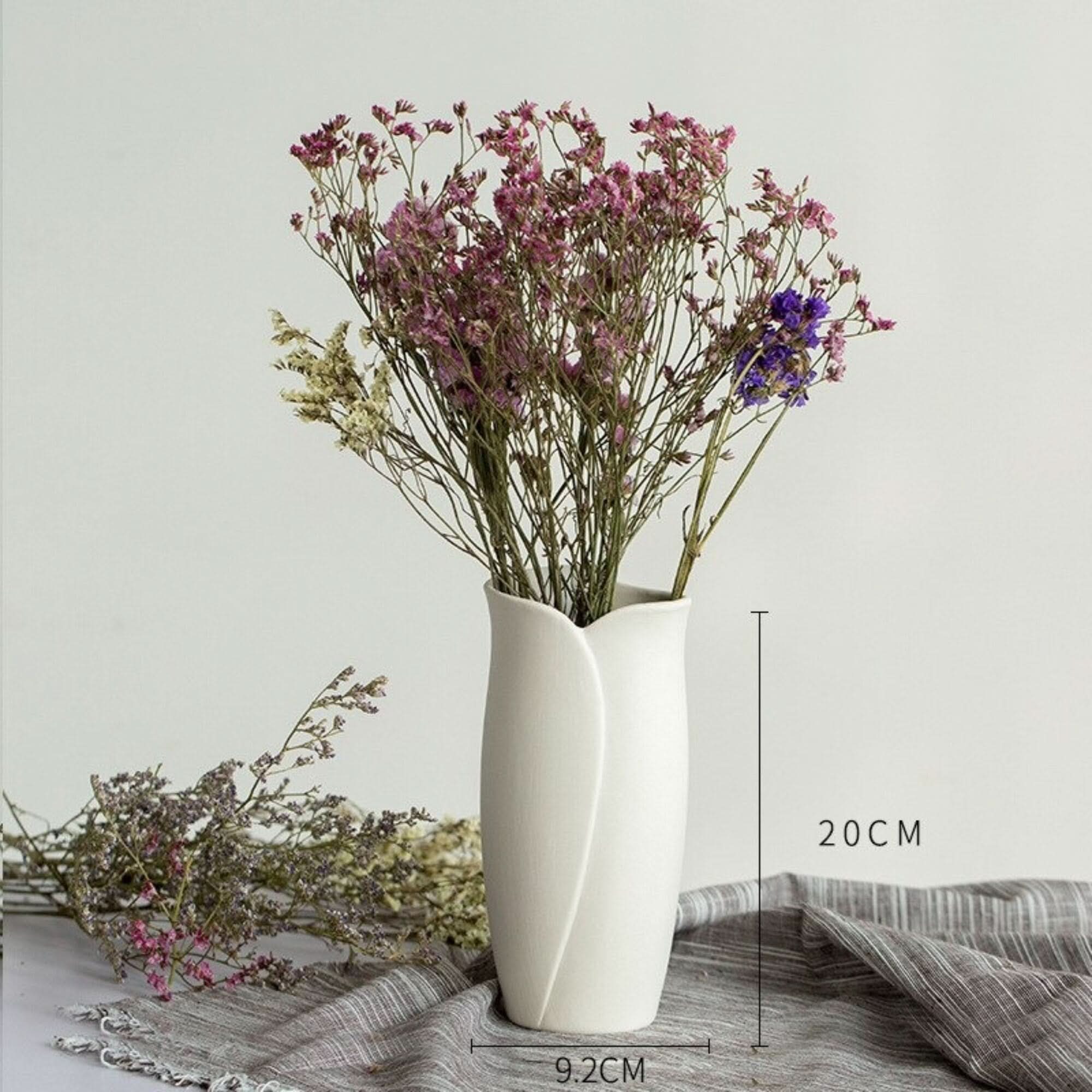 Abstract White Flower Vase with dried flowers on grey fabric background