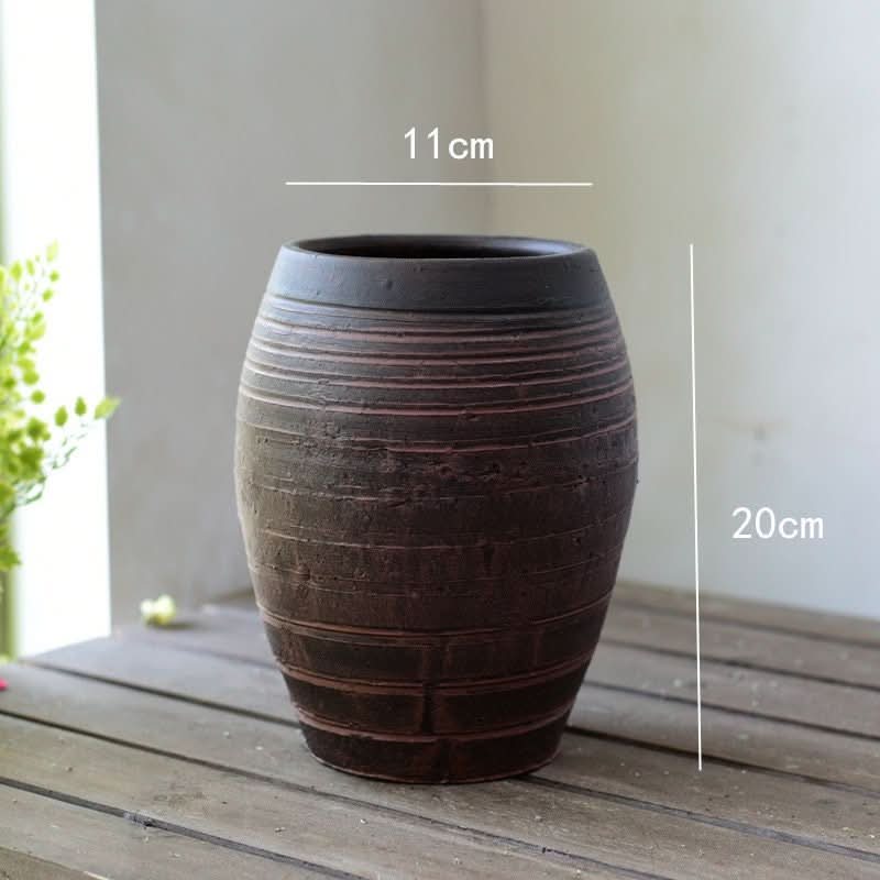 Rustic stoneware vase in a dark, earthy tone with textured horizontal lines.
