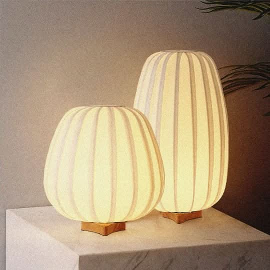 Japandi table lamp with oval shape, white ribbed fabric, wood base, warm glow.