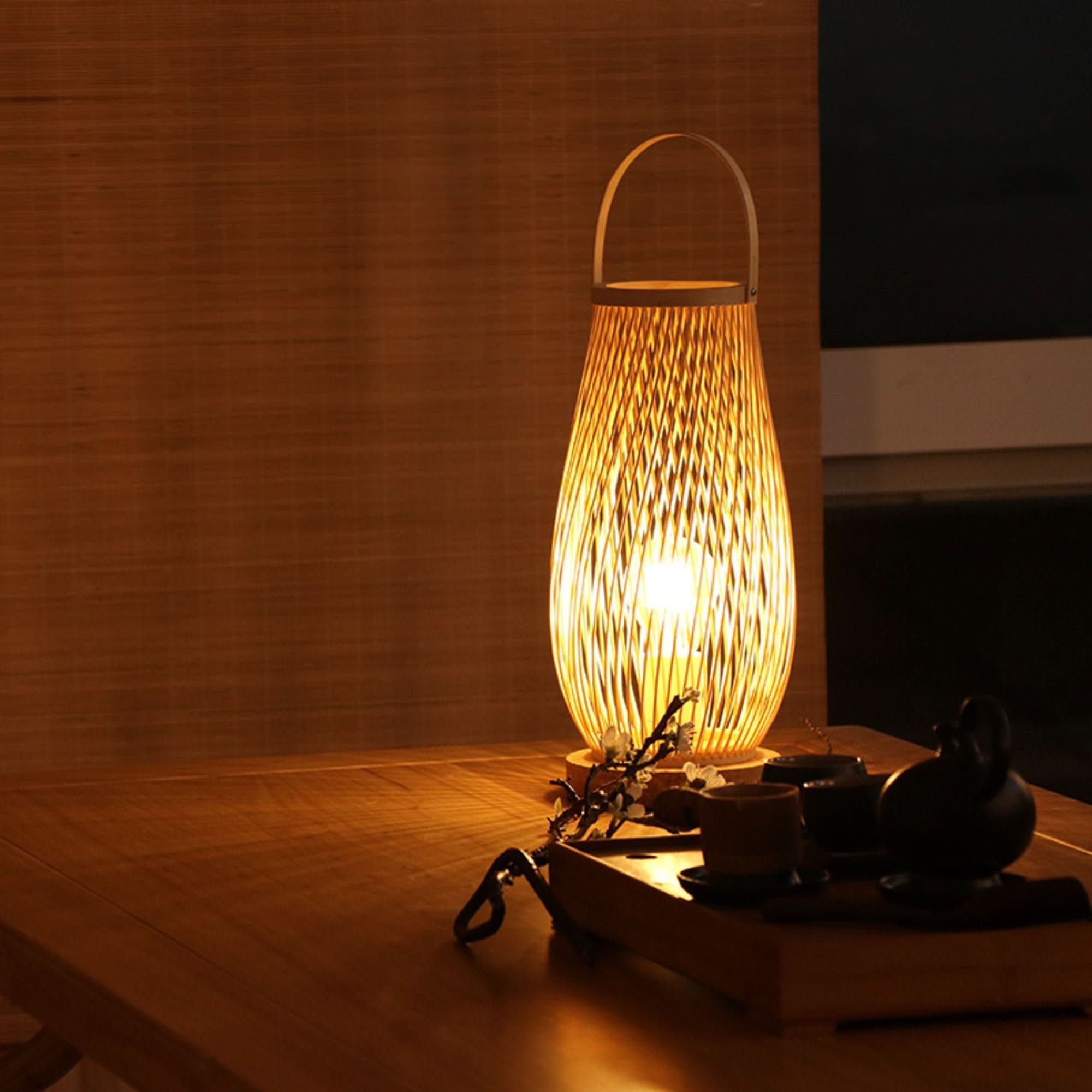 Warm rattan table lamp with handle, emitting soft glow. Perfect bedside or accent light.