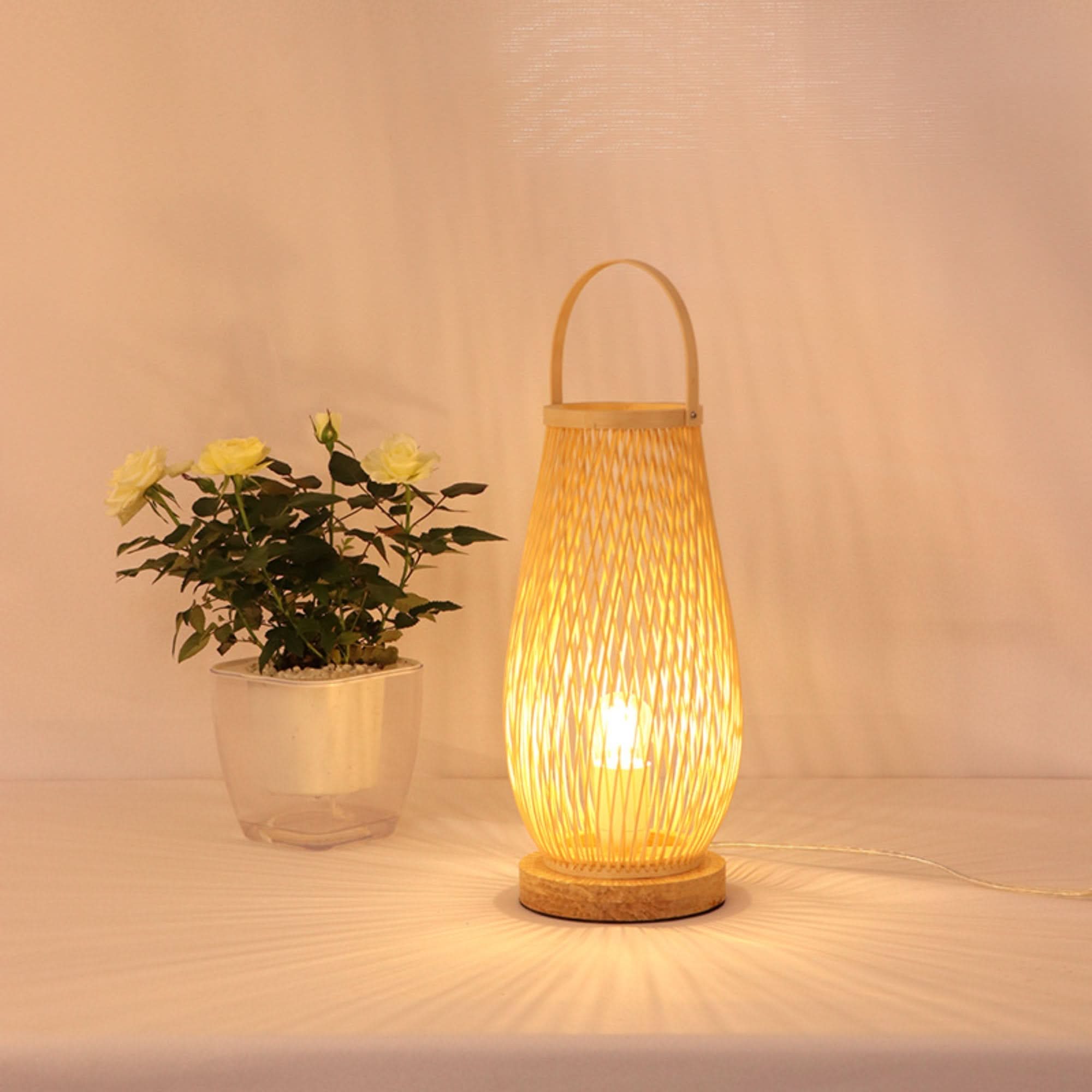 Woven rattan table lamp with handle and wooden base casts warm light.