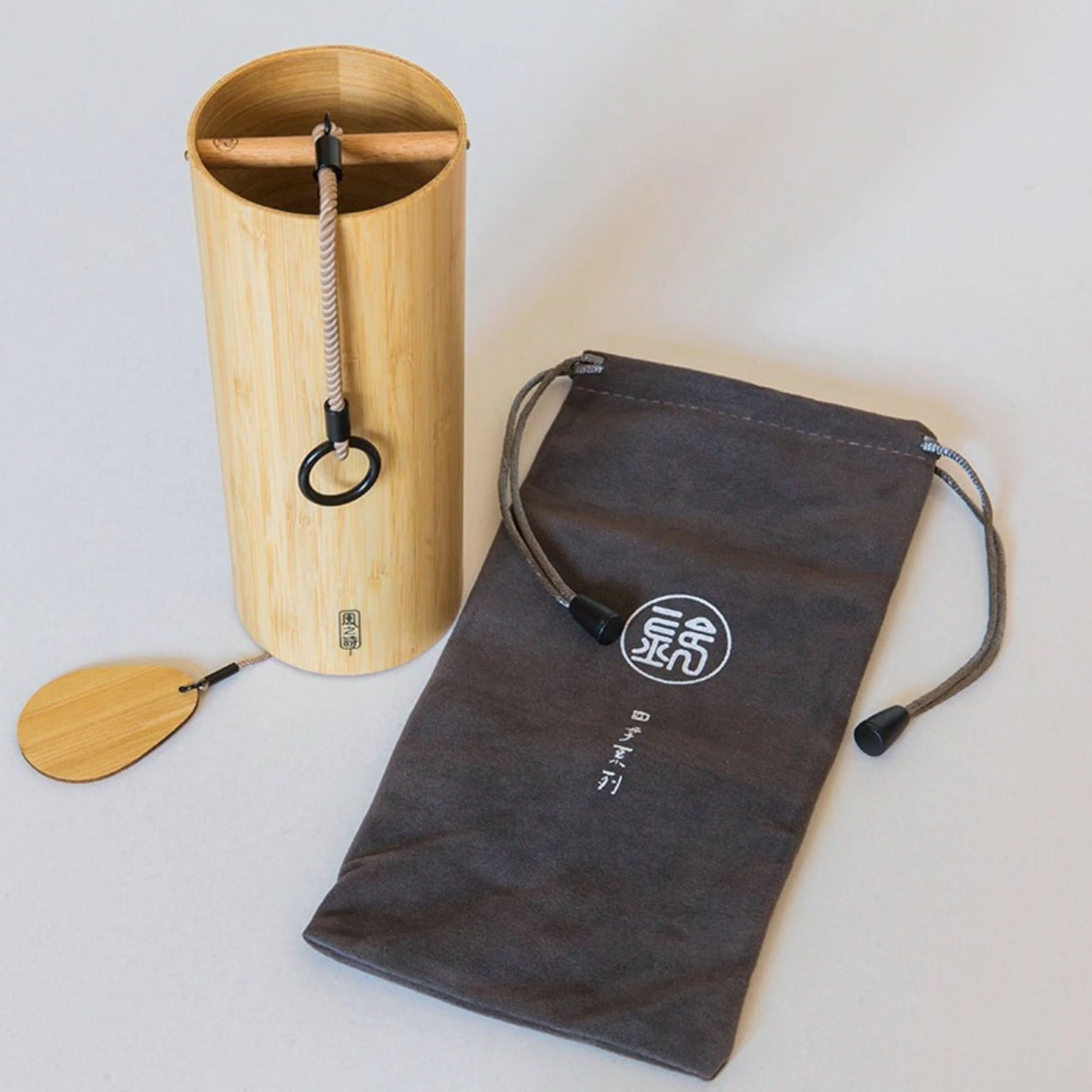 Natural bamboo wind chime 4 melodies with cloth pouch on white surface.