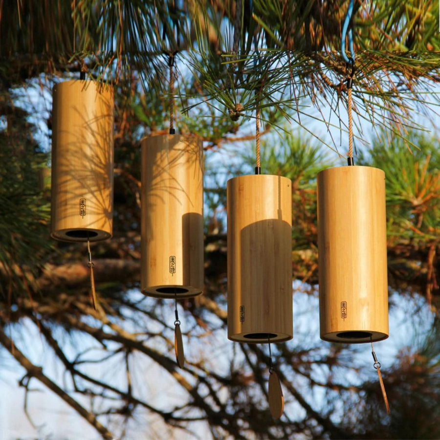Natural bamboo wind chime with 4 melodies hangs on a tree branch, creating peaceful home decor.