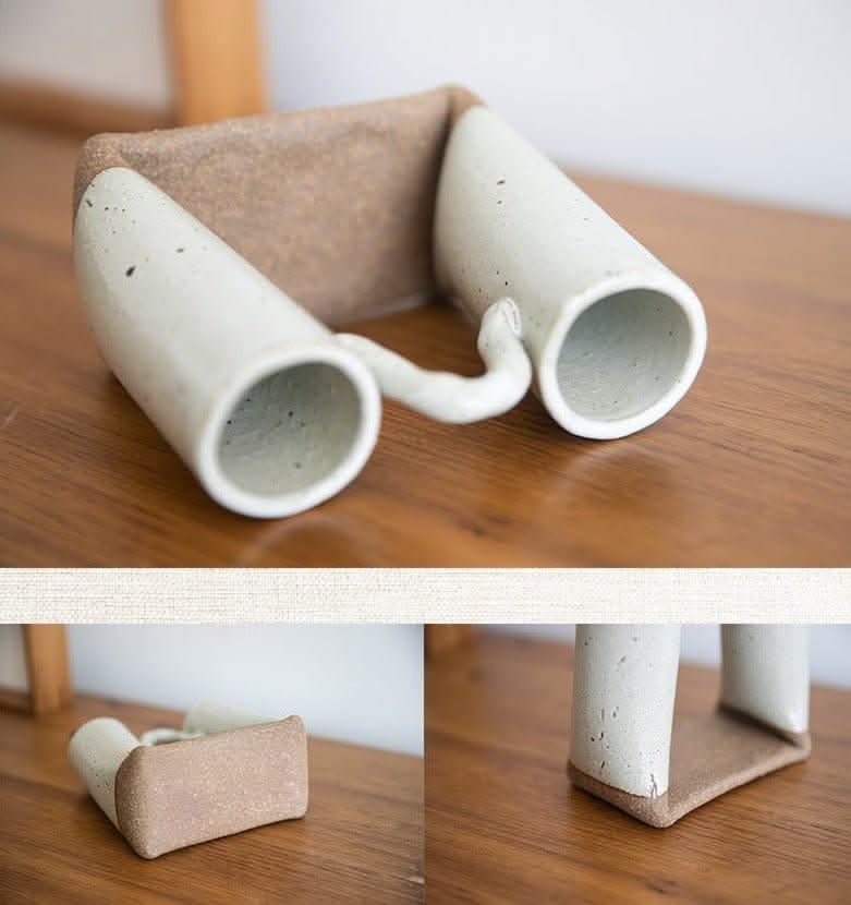 Bent tube textured rough pottery ceramic vase from Japan, white with speckles, on wood.