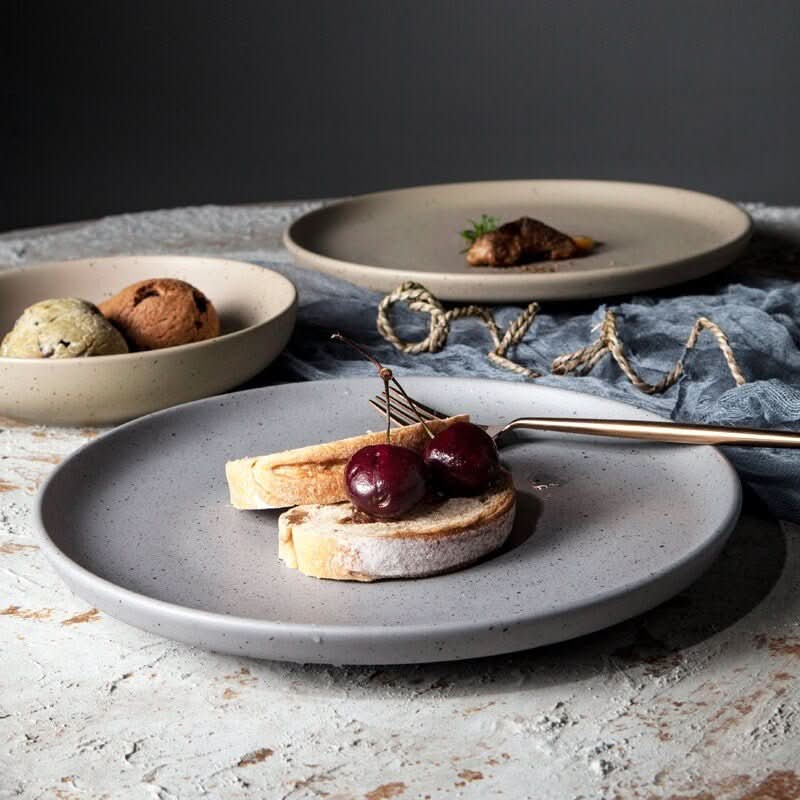 Grey ceramic Nordic plate with cherries and bread, part of all-season tableware.