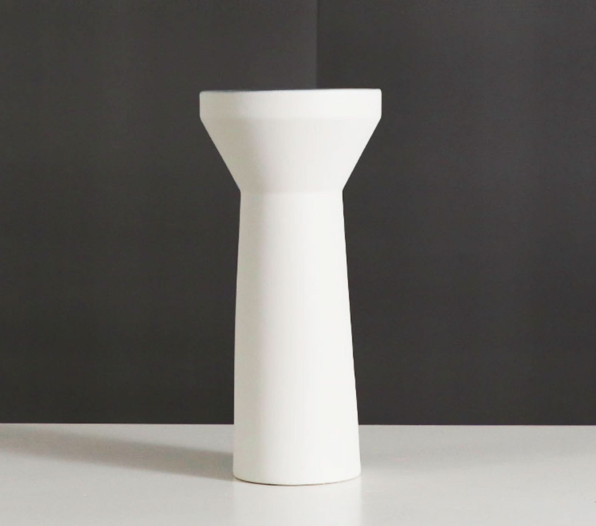 Minimalist white ceramic vase for Zen decor, on a white surface with dark background.