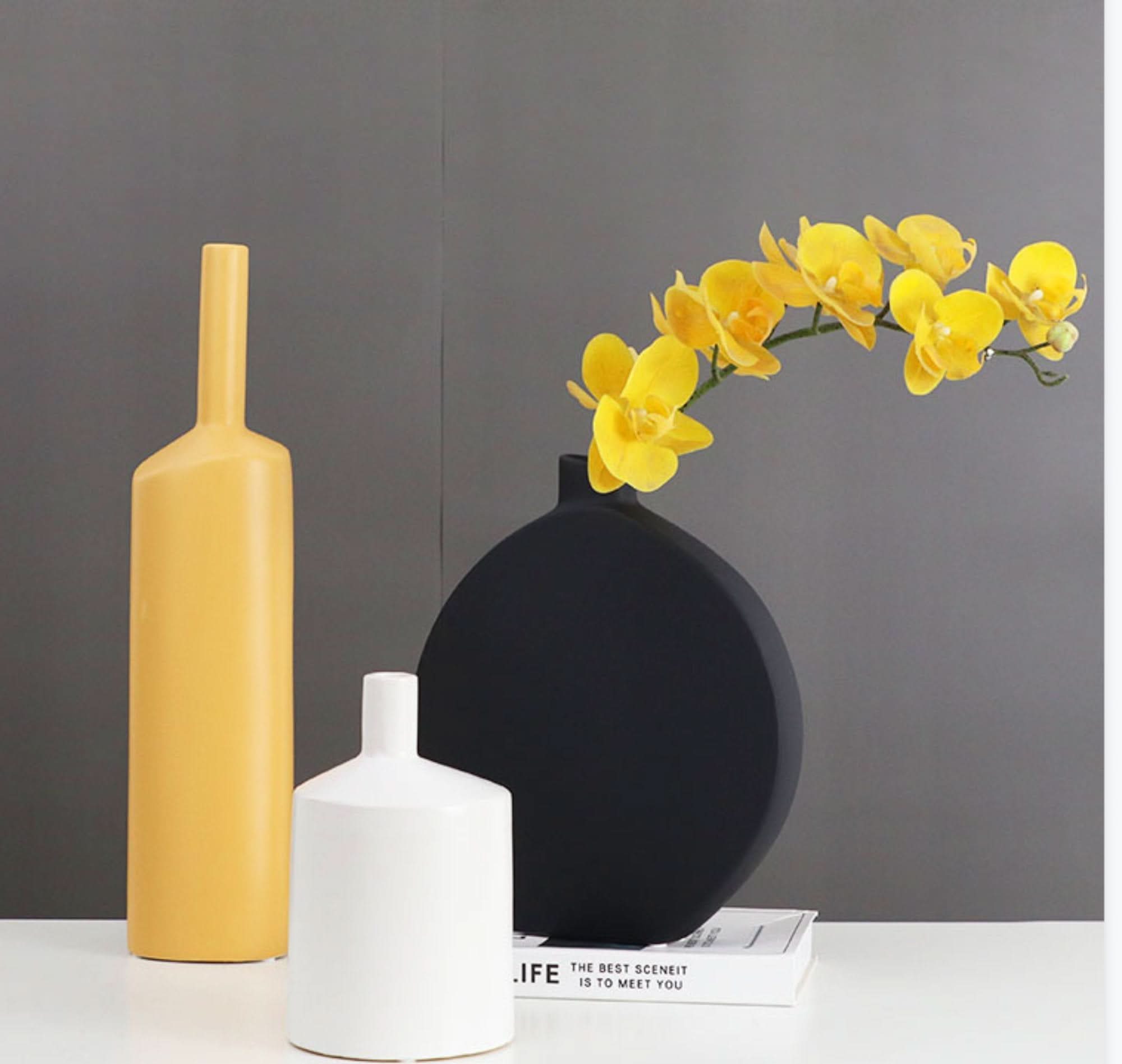 Minimalist black and white ceramic table vase with yellow orchids. Zen decor.