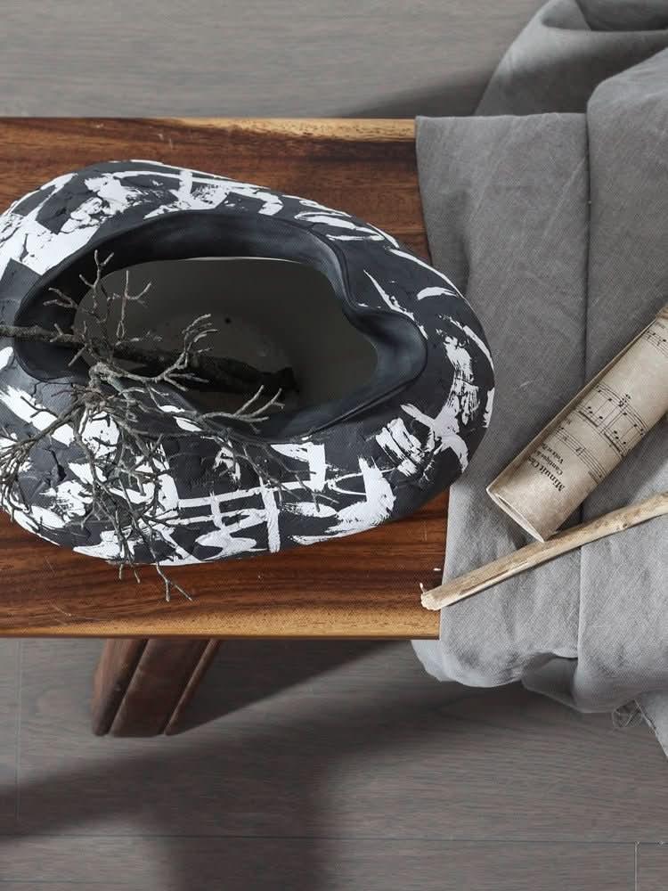 Black irregular wabi-sabi ceramic vase with white brushed effects on wooden surface