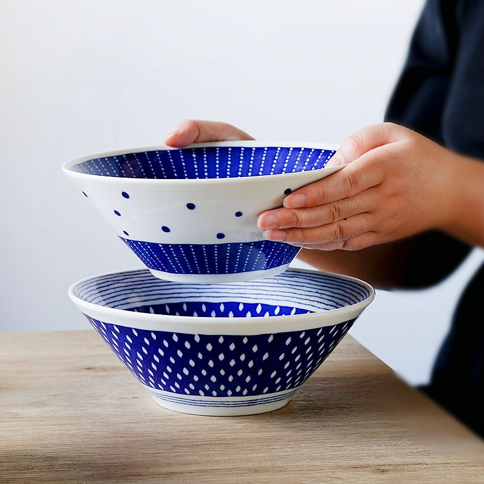 Blue and white pattern ceramic Japanese ramen bowl with dots, stacked on wooden table.