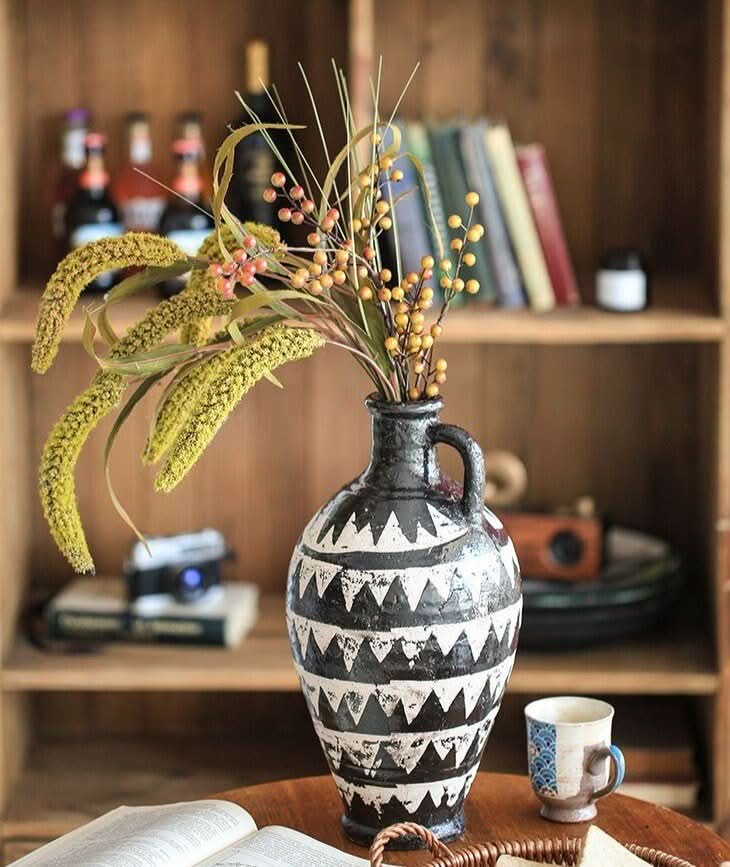 Bold black and white African motif pottery vase with dried flowers.